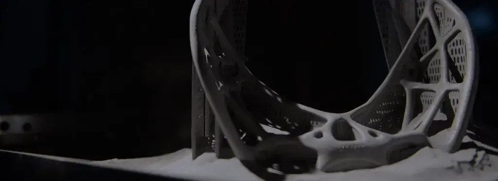 a 3D printed metal part emerging from the printer, surrounded by metal powder