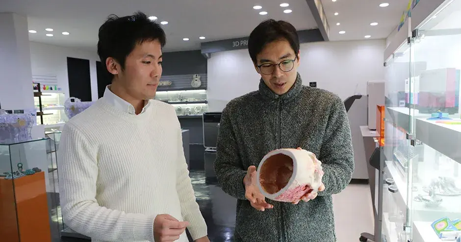 3D 프린트를 보고 있는 2명의 동료