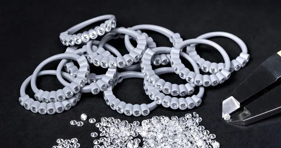 다이아몬드가 세팅된 왁스 성형 반지들, 다이아몬드를 고정하고 있는 캘리퍼, 흩어져있는 다이아몬드